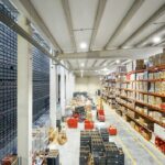 Hochregallager mit Kartons, Kunststoffboxen und markierten Transportwegen