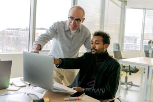 Zwei Kollegen besprechen gemeinsam Ziele an einem Computer im Büro